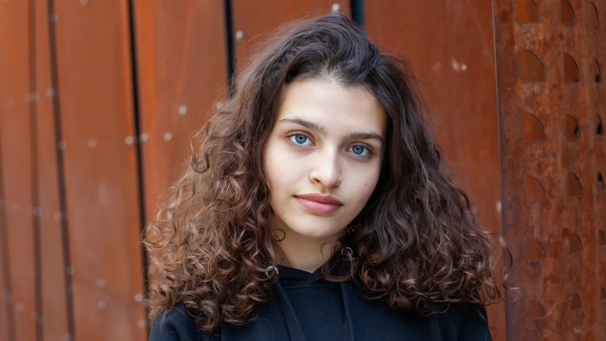 White teenager with curly hair and the most beautiful natural lips. Young girl face.