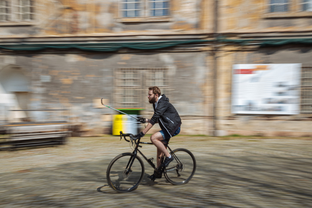 Muž s mikrofonem ukazuje na plátno a láká tím na film.