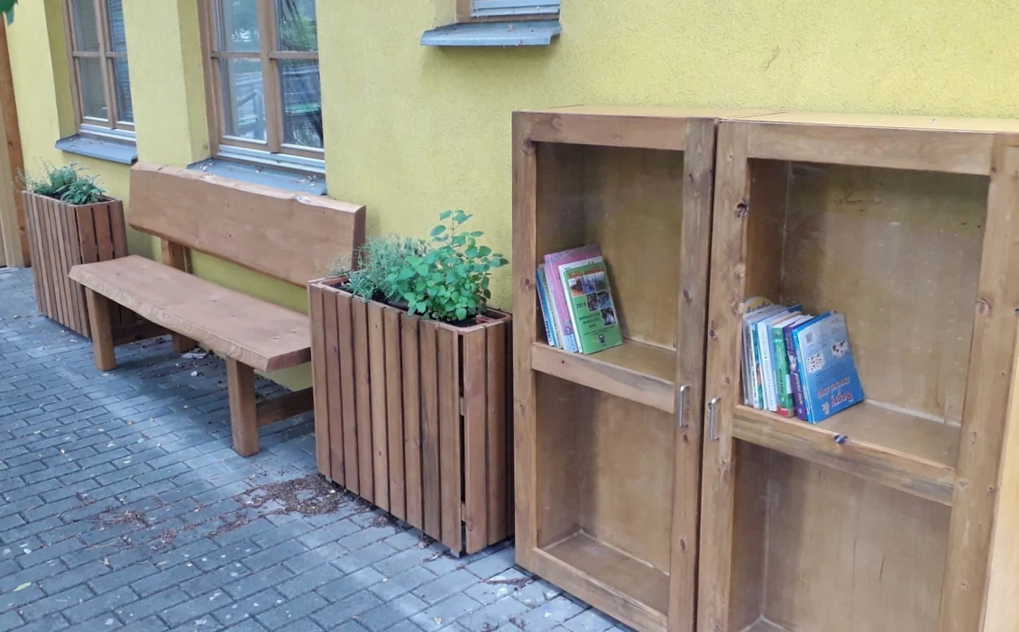 Kolem nové knihobudky jsou rozestavěny květináče s bylinkami a na okolních stromech jsou připevněny hmyzí domečky.