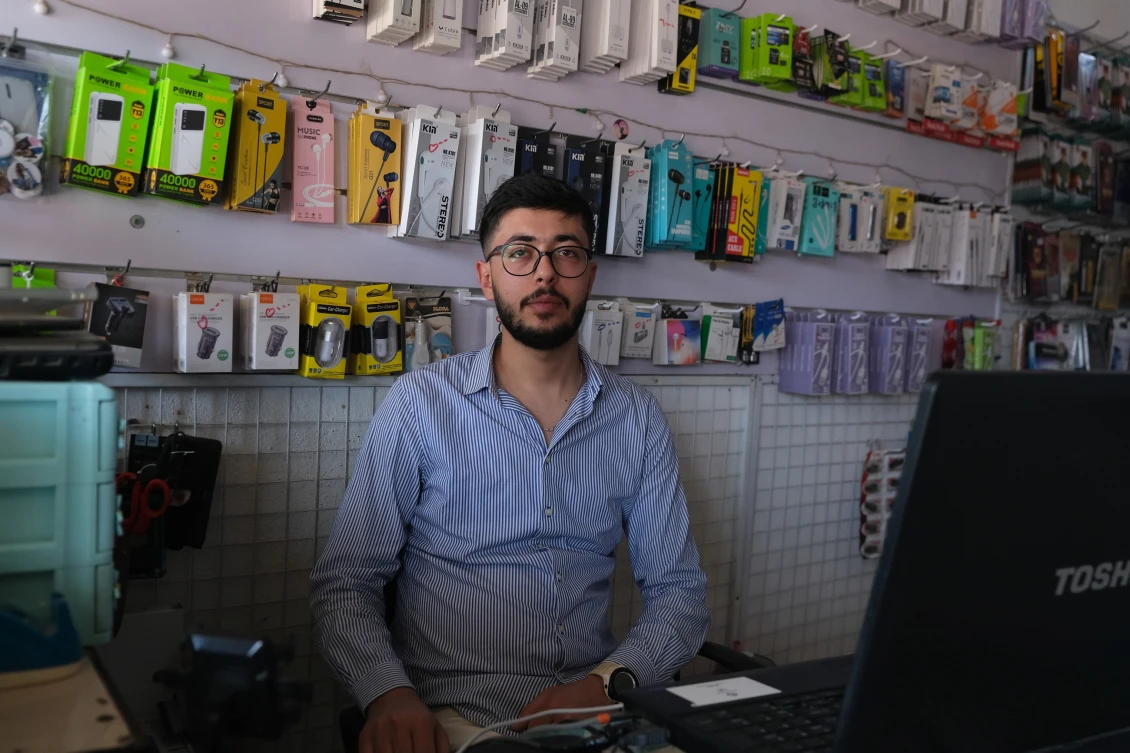Mohammad sedí v obchodě, kte pracuje v táboře Basirma v Kurdistánu v Iráku.